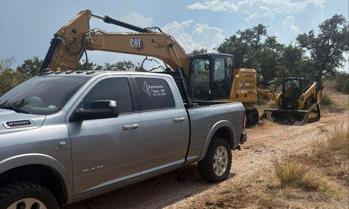 CAT excavator and track loader behind a JSC Earthworks truck on a Hill Country job